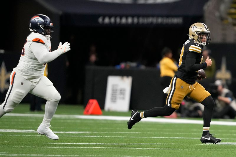 New Orleans Saints quarterback Spencer Rattler runs from Denver Broncos defensive tackle D.J. Jones, left, during the first half of an NFL football game, Thursday, Oct. 17, 2024, in New Orleans. (AP Photo/Gerald Herbert)