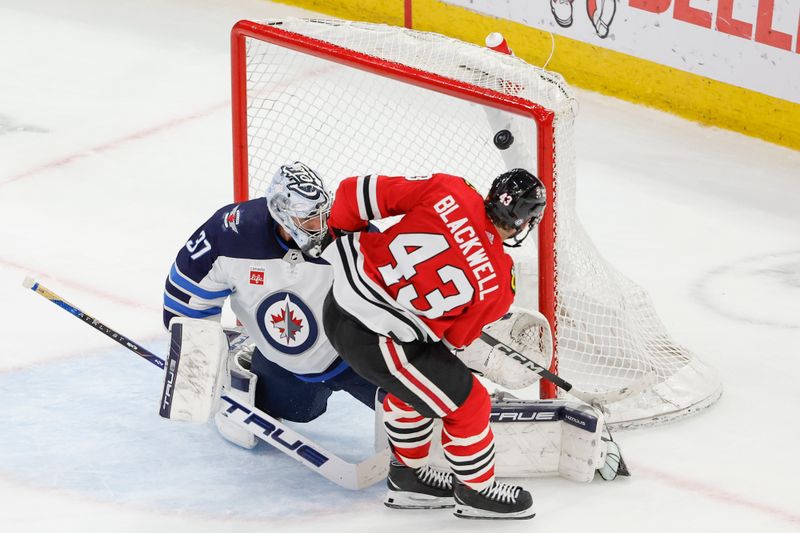 Feb 23, 2024; Chicago, Illinois, USA; Chicago Blackhawks center Colin Blackwell (43) shoots and scores against Winnipeg Jets goaltender Connor Hellebuyck (37) during the second period at United Center. Mandatory Credit: Kamil Krzaczynski-USA TODAY Sports