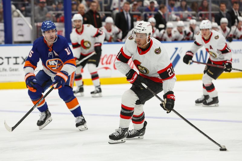 Mar 16, 2024; Elmont, New York, USA;  Ottawa Senators right wing Mathieu Joseph (21) looks to pass while New York Islanders right wing Cal Clutterbuck (15) pursues during the first period at UBS Arena. Mandatory Credit: Thomas Salus-USA TODAY Sports