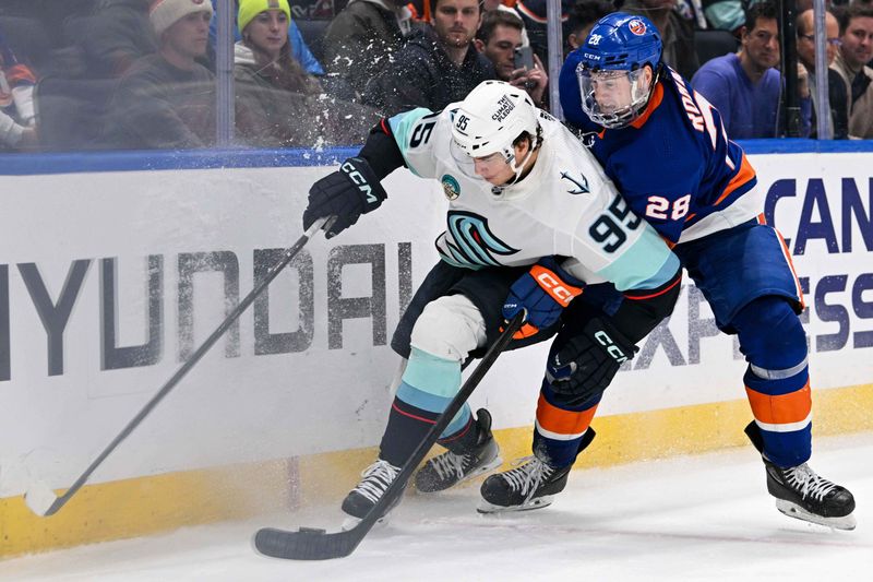 Feb 13, 2024; Elmont, New York, USA; New York Islanders defenseman Alexander Romanov (28) and Seattle Kraken left wing Andre Burakovsky (95) battle for the puck along the boards during the third period at UBS Arena. Mandatory Credit: Dennis Schneidler-USA TODAY Sports