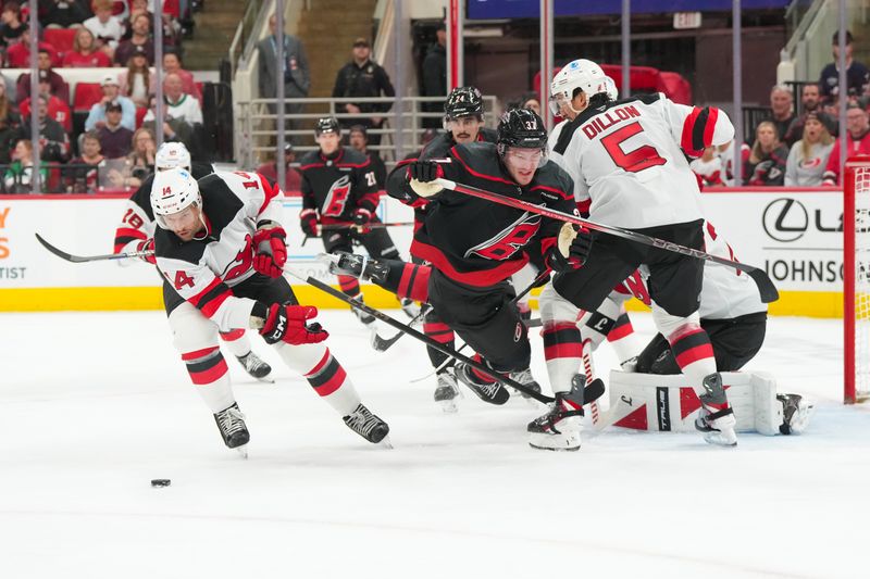 Oct 9, 2025; Raleigh, North Carolina, USA;  Carolina Hurricanes right wing Andrei Svechnikov (37) battle for the puck against New Jersey Devils defenseman Brenden Dillon (5) and center Luke Glendening (14) during the third period at Lenovo Center. Mandatory Credit: James Guillory-Imagn Images