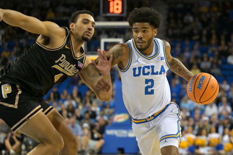 Jan 20, 2026; Los Angeles, California, USA;  UCLA Bruins guard Donovan Dent (2) drives past Purdue Boilermakers forward Trey Kaufman-Renn (4) in the first half at Pauley Pavilion presented by Wescom Financial. Mandatory Credit: Jayne Kamin-Oncea-Imagn Images