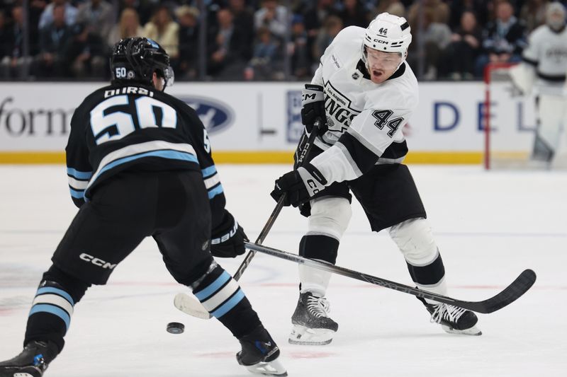Apr 3, 2025; Salt Lake City, Utah, USA; Los Angeles Kings defenseman Mikey Anderson (44) takes a shot against Utah Hockey Club defenseman Sean Durzi (50) during the first period at Delta Center. Mandatory Credit: Rob Gray-Imagn Images