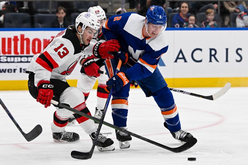 Mar 24, 2024; Elmont, New York, USA;  New York Islanders defenseman Mike Reilly (2) and away New Jersey Devils center Nico Hischier (13) battle for the puck during the first period at UBS Arena. Mandatory Credit: Dennis Schneidler-USA TODAY Sports