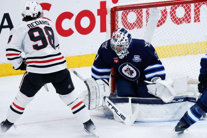 Mar 3, 2026; Winnipeg, Manitoba, CAN;  Winnipeg Jets goalie Connor Hellebuyck (37) makes a save against Chicago Blackhawks forward Connor Bedard (98) during the second period at Canada Life Centre. Mandatory Credit: Terrence Lee-Imagn Images