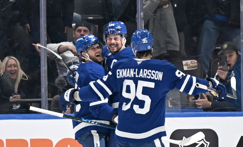 Oct 16, 2025; Toronto, Ontario, CAN; Toronto Maple Leafs forward Auston Matthews (34) celebrates with forward William Nylander (88) and defenseman Oliver Ekman-Larsson (95) after scoring the winning goal against the New York Rangers in overtime at Scotiabank Arena. Mandatory Credit: Dan Hamilton-Imagn Images