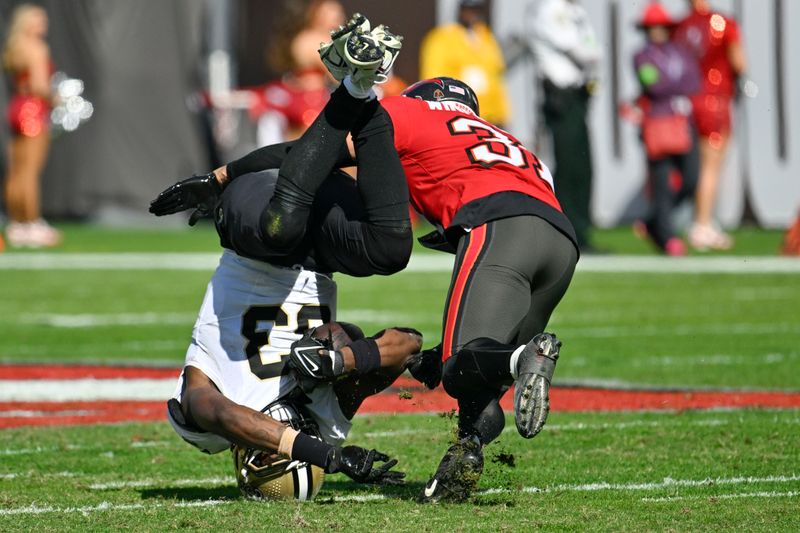 New Orleans Saints tight end Juwan Johnson (83) is brought down by Tampa Bay Buccaneers safety Antoine Winfield Jr. (31) on a pass reception in the first half of an NFL football game in Tampa, Fla., Sunday, Dec. 31, 2023. (AP Photo/Jason Behnken)