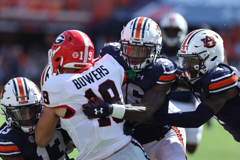 Sep 30, 2023; Auburn, Alabama, USA; Georgia Bulldogs tight end Brock Bowers (19) is stopped by Auburn Tigers linebacker Cam Riley (13), cornerback Jaylin Simpson (36), and cornerback D.J. James (4) during the first quarter at Jordan-Hare Stadium. Mandatory Credit: John Reed-USA TODAY Sports