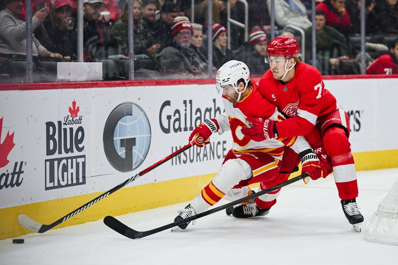 Nov 27, 2024; Detroit, Michigan, USA; Calgary Flames center Kevin Rooney (21) and Detroit Red Wings defenseman Simon Edvinsson (77) battle for the puck during the first period at Little Caesars Arena. Mandatory Credit: Tim Fuller-Imagn Images