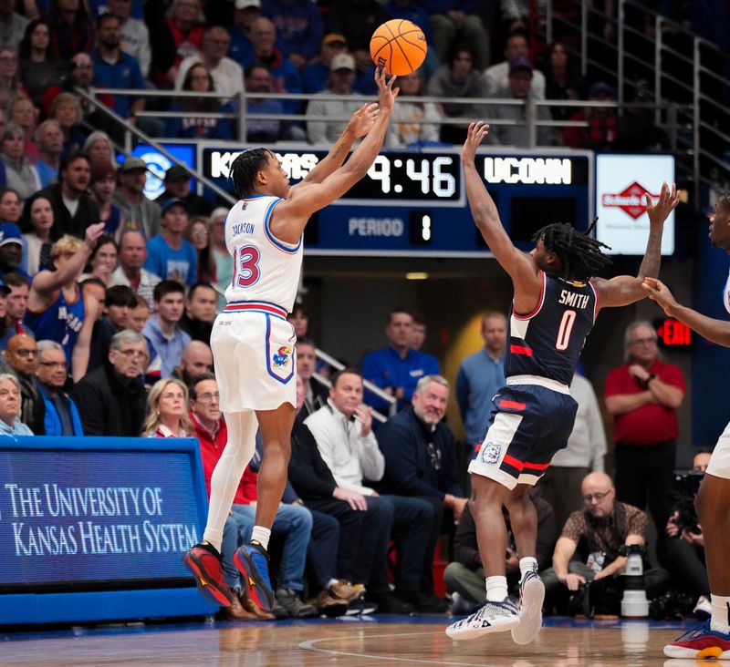 Dec 2, 2025; Lawrence, Kansas, USA; Kansas Jayhawks guard Elmarko Jackson (13) shoots a three point basket as UConn Huskies guard Malachi Smith (0) defends during the first half of the game at Allen Fieldhouse. Mandatory Credit: Denny Medley-Imagn Images