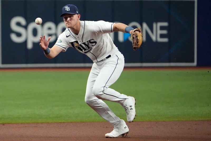 Aug 23, 2023; St. Petersburg, Florida, USA; Tampa Bay Rays second baseman Curtis Mead (25) bare hands a ball hit by Colorado Rockies third baseman Ryan McMahon (24) during the first inning at Tropicana Field. McMahon was safe at first. Mandatory Credit: Dave Nelson-USA TODAY Sports