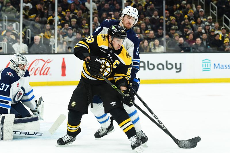 Jan 30, 2025; Boston, Massachusetts, USA; Boston Bruins left wing Brad Marchand (63) and Winnipeg Jets defenseman Dylan Samberg (54) battle for position in front of goaltender Connor Hellebuyck (37) during the first period at TD Garden. Mandatory Credit: Bob DeChiara-Imagn Images