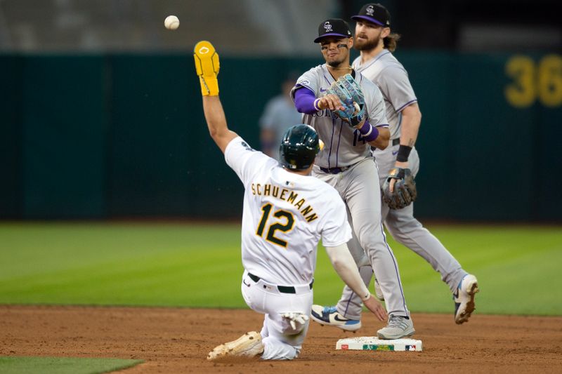 May 22, 2024; Oakland, California, USA; Colorado Rockies shortstop Ezequiel Tovar (14) throws over Oakland Athletics shortstop Max Schuemann (12) to complete a double play during the sixth inning at Oakland-Alameda County Coliseum. Mandatory Credit: D. Ross Cameron-USA TODAY Sports