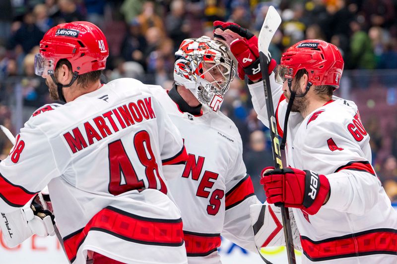 Oct 28, 2024; Vancouver, British Columbia, CAN; Carolina Hurricanes forward Jordan Martinook (48) and defenseman Shayne Gostisbehere (4) and goalie Pyotr Kochetkov (52) celebrate their victory against the Vancouver Canucks at Rogers Arena. Mandatory Credit: Bob Frid-Imagn Images