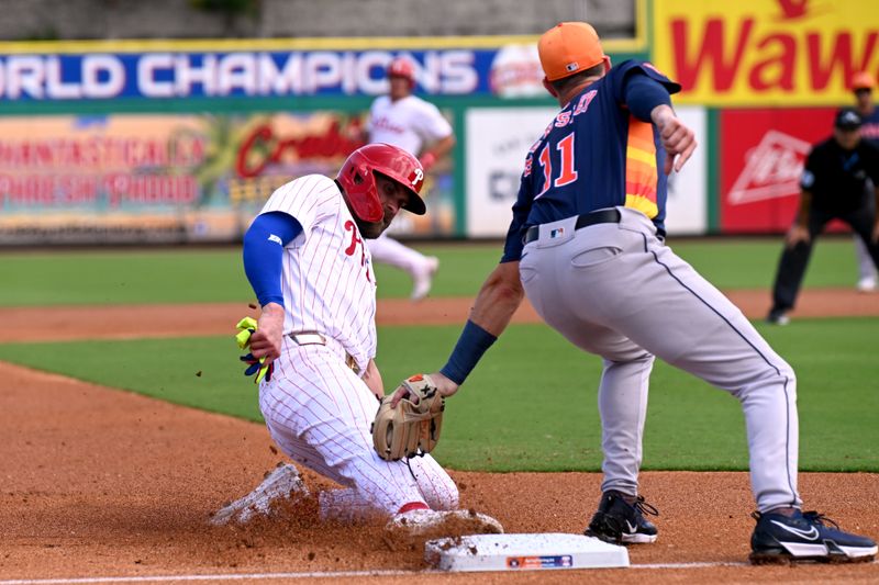 Mar 8, 2024; Clearwater, Florida, USA; Philadelphia Phillies first baseman Bryce Harper (3) slides past the tag of Houston Astros third baseman David Hensley (11) in the first inning of the spring training game at BayCare Ballpark. Mandatory Credit: Jonathan Dyer-USA TODAY Sports