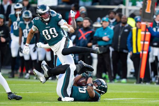 Philadelphia Eagles running back Saquon Barkley (26) gets tripped up as he runs with the ball with wide receiver Johnny Wilson (89) trying to avoid him during the NFL football game against the Carolina Panthers, Sunday, Dec. 8, 2024, in Philadelphia. Saquon Barkley sets the Philadelphia Eagles single season rushing record on this run.The Eagles won 22-16. (AP Photo/Chris Szagola)