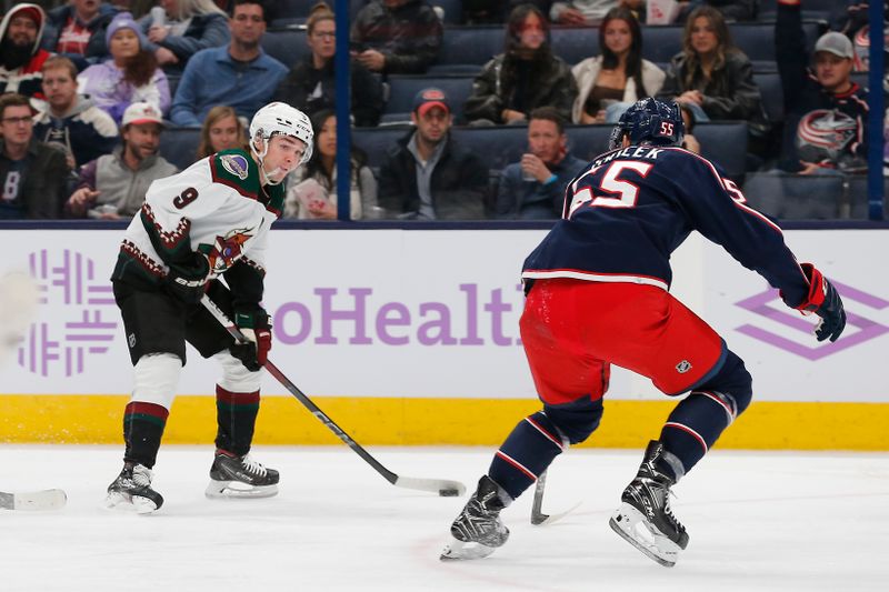 Nov 16, 2023; Columbus, Ohio, USA; Arizona Coyotes center Clayton Keller (9) passes the puck as Columbus Blue Jackets defenseman David Jiricek (55) defends during the third period at Nationwide Arena. Mandatory Credit: Russell LaBounty-USA TODAY Sports