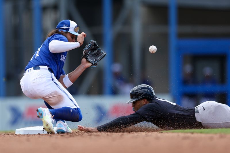 Mar 12, 2024; Dunedin, Florida, USA;  New York Yankees center fielder Trent Grisham (12) steals second base from Toronto Blue Jays shortstop Bo Bichette (11) in the fifth inning at TD Ballpark. Mandatory Credit: Nathan Ray Seebeck-USA TODAY Sports