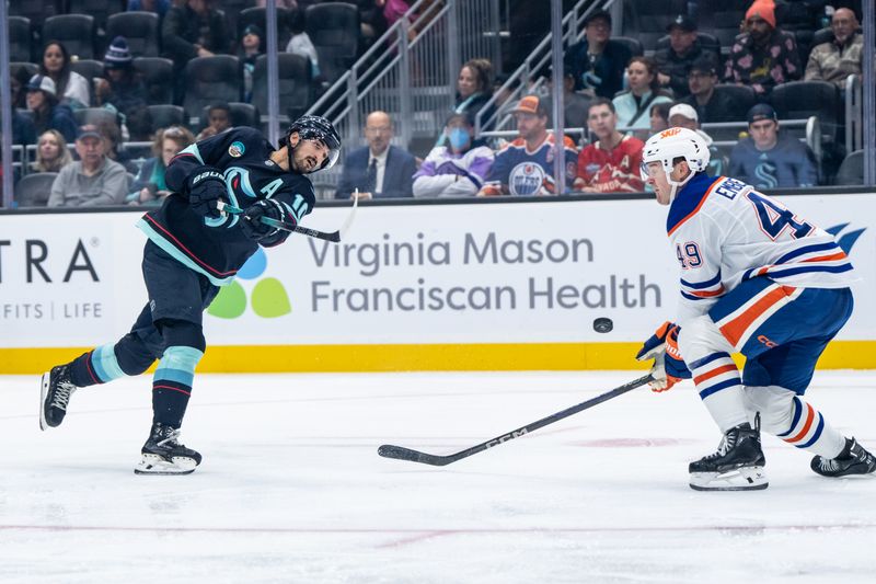 Oct 25, 2025; Seattle, Washington, USA; Seattle Kraken forward Matty Beniers (10) takes a shot against Edmonton Oilers defenseman Ty Emberson (49) during the second period at Climate Pledge Arena. Mandatory Credit: Stephen Brashear-Imagn Images