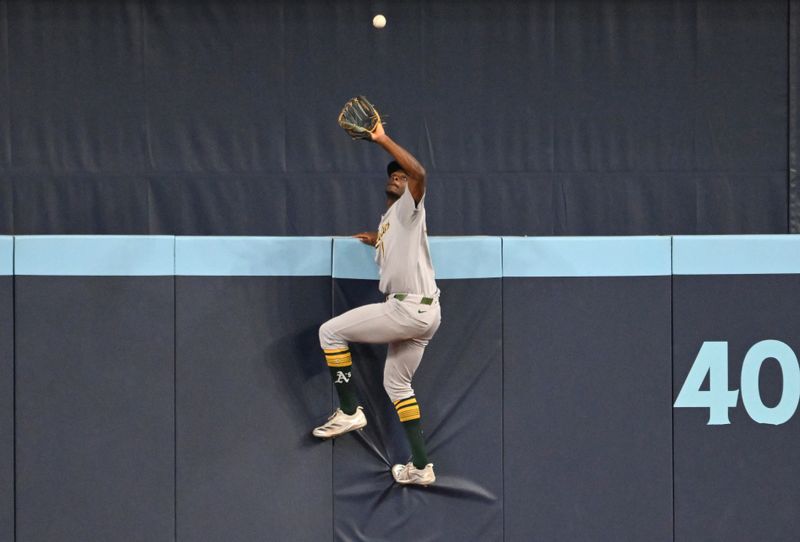 May 30, 2025; Toronto, Ontario, CAN; Athletics center fielder Denzel Clarke (1) climbs the outfield wall to catch a fly ball hit by Toronto Blue Jays catcher Alejandro Kirk (not shown) in the fifth inning at Rogers Centre. Mandatory Credit: Dan Hamilton-Imagn Images