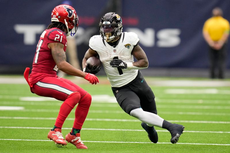 Jacksonville Jaguars running back Travis Etienne Jr. (1) runs the ball as Houston Texans cornerback Steven Nelson (21) moves in to make the stop in the second half of an NFL football game in Houston, Sunday, Nov. 26, 2023. (AP Photo/Eric Christian Smith)