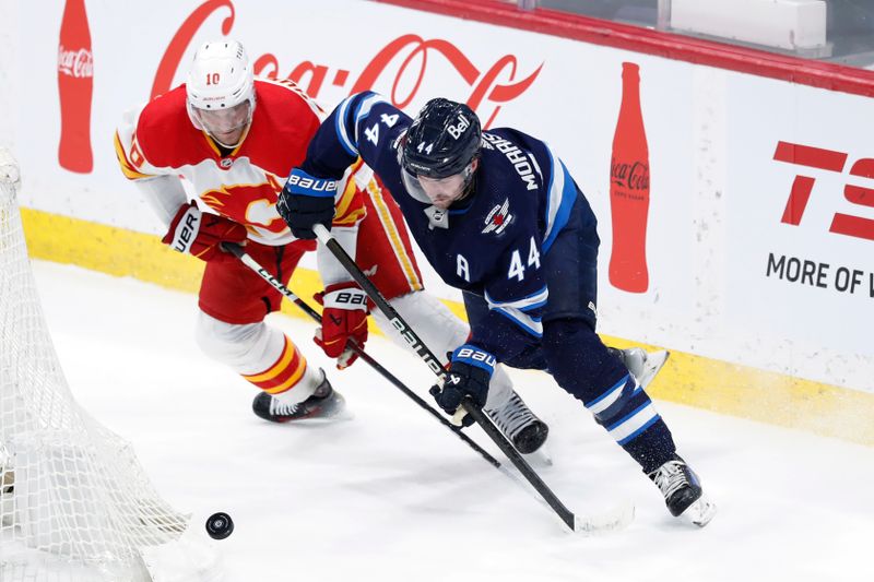 Apr 4, 2024; Winnipeg, Manitoba, CAN; Calgary Flames center Jonathan Huberdeau (10) and Winnipeg Jets defenseman Josh Morrissey (44) chase after the puck in the third period at Canada Life Centre. Mandatory Credit: James Carey Lauder-USA TODAY Sports