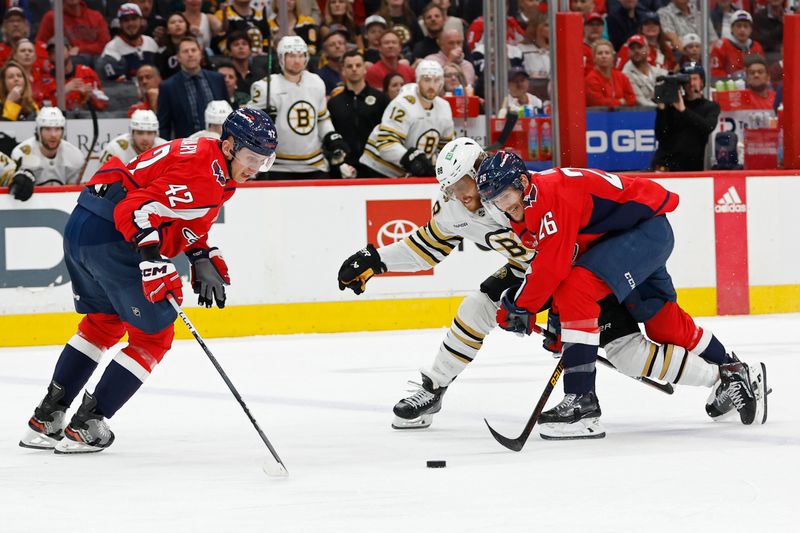 Apr 15, 2024; Washington, District of Columbia, USA; Boston Bruins right wing David Pastrnak (88) and Washington Capitals center Nic Dowd (26) battle for the puck in front of Capitals defenseman Martin Fehervary (42) in the second period at Capital One Arena. Mandatory Credit: Geoff Burke-USA TODAY Sports