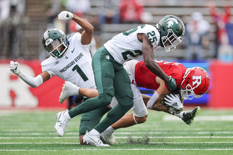 Oct 14, 2023; Piscataway, New Jersey, USA; Rutgers Scarlet Knights wide receiver Christian Dremel (6) is tackled by Michigan State Spartans defensive back Chance Rucker (25) and defensive back Jaden Mangham (1)  during the first half at SHI Stadium. Mandatory Credit: Vincent Carchietta-USA TODAY Sports