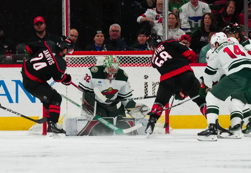 Jan 21, 2024; Raleigh, North Carolina, USA;  Minnesota Wild goaltender Filip Gustavsson (32) stops the scoring attempt by left wing Michael Bunting (58) and Carolina Hurricanes center Seth Jarvis (24) during the second period at PNC Arena. Mandatory Credit: James Guillory-USA TODAY Sports