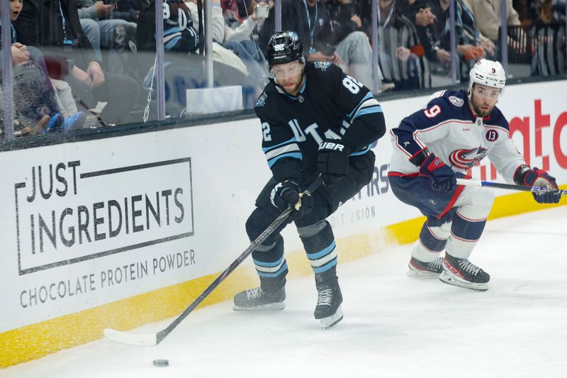 Jan 31, 2025; Salt Lake City, Utah, USA;  Utah Hockey Club center Kevin Stenlund (82) tries to control the puck before Columbus Blue Jackets defenseman Ivan Provorov (9) can get to it during the second period at Delta Center. Mandatory Credit: Chris Nicoll-Imagn Images