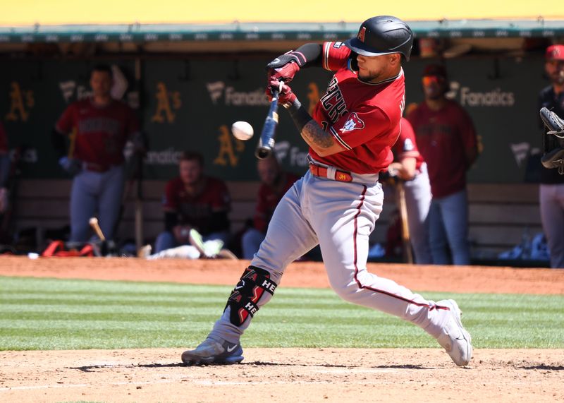 May 17, 2023; Oakland, California, USA; Arizona Diamondbacks catcher Jose Herrera (11) hits a sacrifice fly to send in an RBI against Oakland Athletics during the ninth inning at Oakland-Alameda County Coliseum. Mandatory Credit: Kelley L Cox-USA TODAY Sports