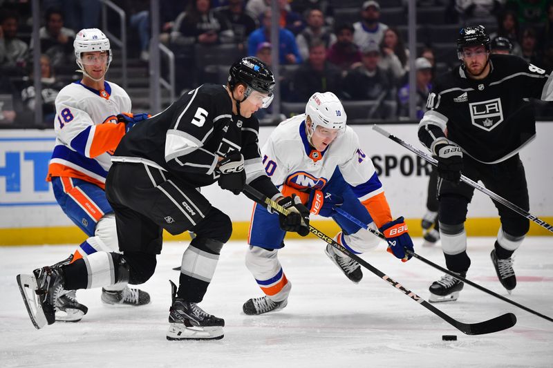 Mar 11, 2024; Los Angeles, California, USA; Los Angeles Kings defenseman Andreas Englund (5) plays for the puck against New York Islanders right wing Simon Holmstrom (10) during the third period at Crypto.com Arena. Mandatory Credit: Gary A. Vasquez-USA TODAY Sports