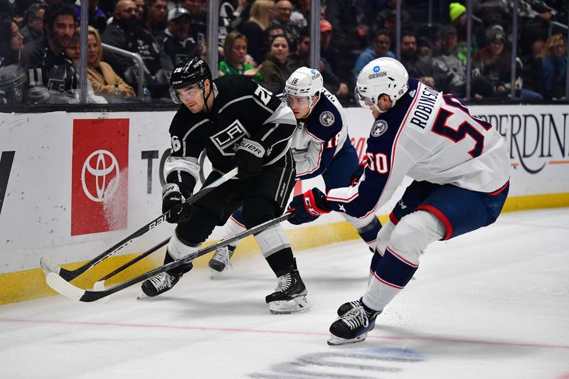 Mar 16, 2023; Los Angeles, California, USA; Los Angeles Kings defenseman Sean Walker (26) clears the puck agaist Columbus Blue Jackets left wing Eric Robinson (50) and center Lane Pederson (18) during the third period at Crypto.com Arena. Mandatory Credit: Gary A. Vasquez-USA TODAY Sports