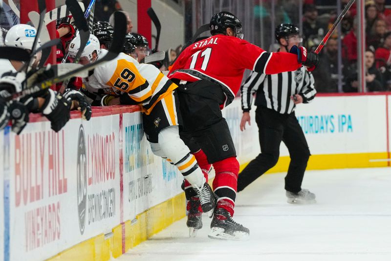 Dec 18, 2022; Raleigh, North Carolina, USA; Carolina Hurricanes center Jordan Staal (11) checks Pittsburgh Penguins left wing Jake Guentzel (59) during the third period at PNC Arena. Mandatory Credit: James Guillory-USA TODAY Sports