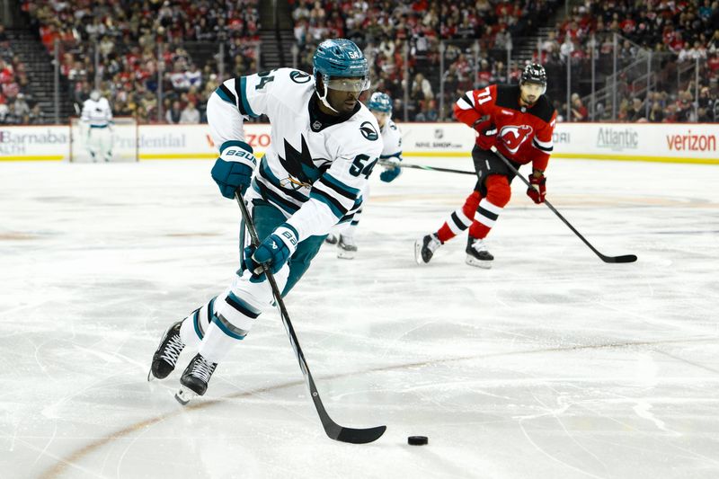 Nov 10, 2024; Newark, New Jersey, USA; San Jose Sharks right wing Givani Smith (54) skates with the puck as New Jersey Devils defenseman Jonas Siegenthaler (71) trails during the first period at Prudential Center. Mandatory Credit: John Jones-Imagn Images