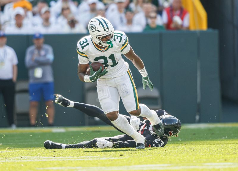 Green Bay Packers running back Emanuel Wilson (31) runs against Houston Texans safety Eric Murray (23) during an NFL football game Sunday, Oct. 20, 2024, in Green Bay, Wis. (AP Photo/Jeffrey Phelps