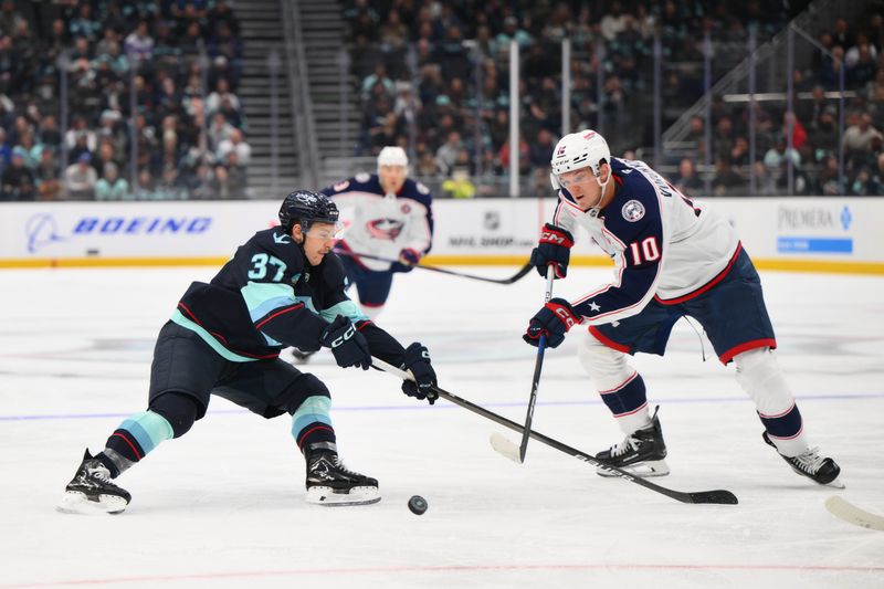 Nov 12, 2024; Seattle, Washington, USA; Columbus Blue Jackets left wing Dmitri Voronkov (10) passes the puck past Seattle Kraken center Yanni Gourde (37) during the second period at Climate Pledge Arena. Mandatory Credit: Steven Bisig-Imagn Images