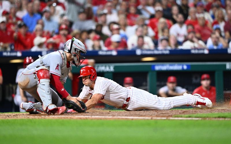 Aug 29, 2023; Philadelphia, Pennsylvania, USA; Philadelphia Phillies catcher J.T. Realmuto (10) slides past Los Angeles Angels catcher Logan O'Hoppe (14) to score in the sixth inning at Citizens Bank Park. Mandatory Credit: Kyle Ross-USA TODAY Sports