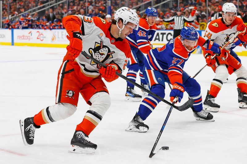 Mar 4, 2025; Edmonton, Alberta, CAN; Edmonton Oilers defensemen Brett Kulak (27)  tries to knock the puck away from Anaheim Ducks forward Mason MacTavish (23) during the second period at Rogers Place. Mandatory Credit: Perry Nelson-Imagn Images