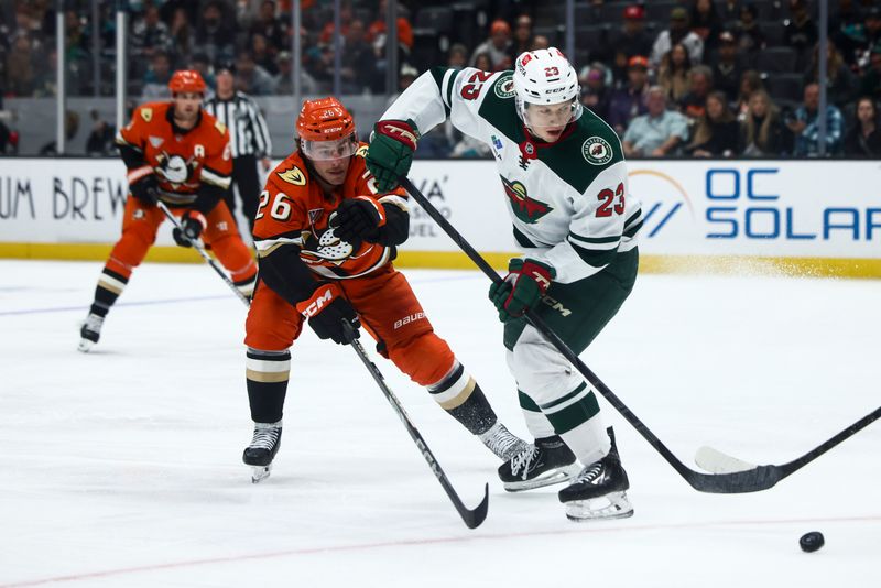 Nov 8, 2024; Anaheim, California, USA; Minnesota Wild center Marco Rossi (23) passes with the puck behind him during the third period of a hockey game against Anaheim Ducks left wing Brock McGinn (26) at Honda Center. Mandatory Credit: Jessica Alcheh-Imagn Images