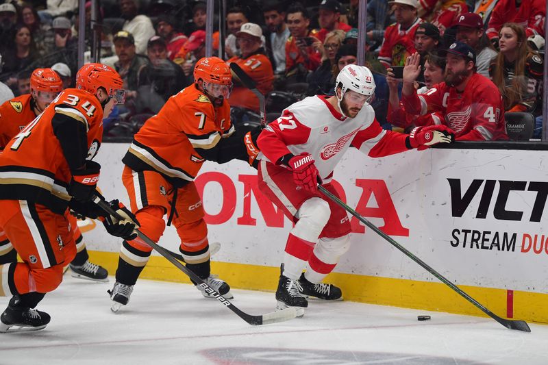 Nov 15, 2024; Anaheim, California, USA; Detroit Red Wings center Michael Rasmussen (27) moves the puck against Anaheim Ducks defenseman Radko Gudas (7) and defenseman Pavel Mintyukov (34) during the first period at Honda Center. Mandatory Credit: Gary A. Vasquez-Imagn Images