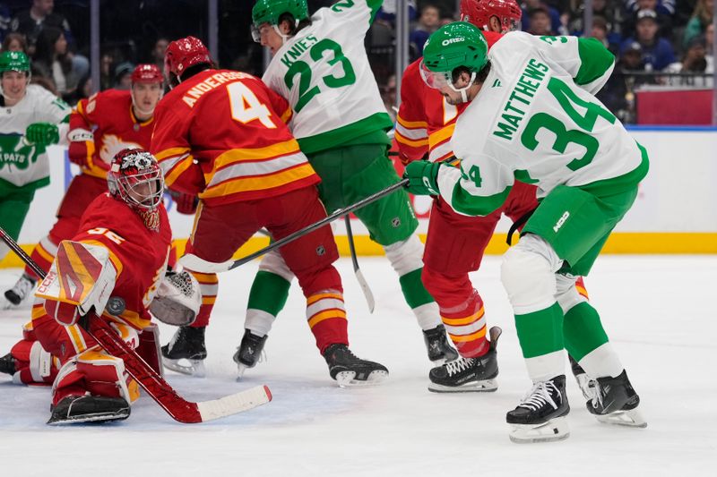 Mar 17, 2025; Toronto, Ontario, CAN; Calgary Flames goaltender Dustin Wolf (32) makes a save against Toronto Maple Leafs forward Auston Matthews (34) during the first period at Scotiabank Arena. Mandatory Credit: John E. Sokolowski-Imagn Images