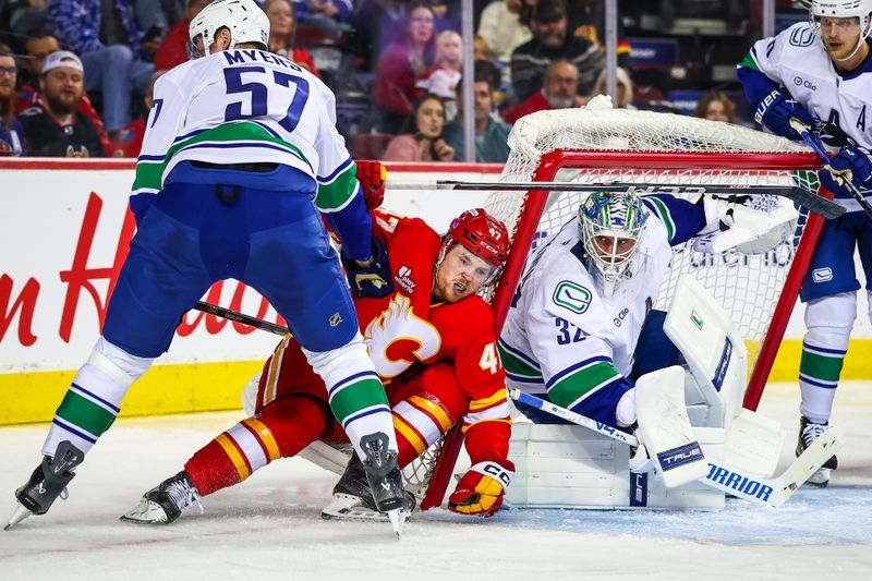 Oct 1, 2025; Calgary, Alberta, CAN; Vancouver Canucks defenseman Tyler Myers (57) and Calgary Flames center Connor Zary (47) battles for the puck in front of Vancouver Canucks goaltender Kevin Lankinen (32) during the second period at Scotiabank Saddledome. Mandatory Credit: Sergei Belski-Imagn Images