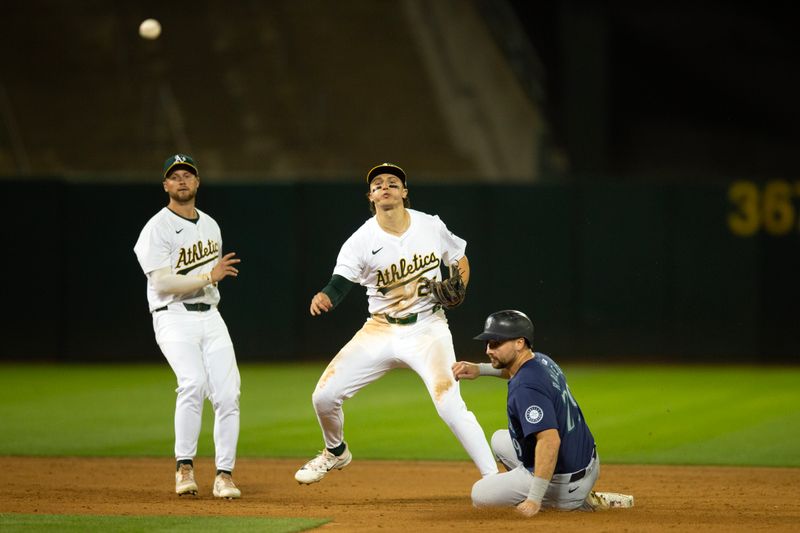 Jun 5, 2024; Oakland, California, USA; Oakland Athletics second baseman Zack Gelof (20) throws over Seattle Mariners catcher Cal Raleigh (29) to complete a game-ending double play during the ninth inning at Oakland-Alameda County Coliseum. Mandatory Credit: D. Ross Cameron-USA TODAY Sports