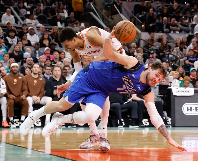 SAN ANTONIO, TX - MARCH 19:  Luka Doncic #77 of the Dallas Mavericks is fouled as he drives past Victor Wembanyama #1 of the San Antonio Spurs in the second half at Frost Bank Center on March 19, 2024 in San Antonio, Texas. NOTE TO USER: User expressly acknowledges and agrees that, by downloading and or using this photograph, User is consenting to terms and conditions of the Getty Images License Agreement. (Photo by Ronald Cortes/Getty Images)