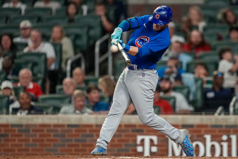 Sep 27, 2023; Cumberland, Georgia, USA; Chicago Cubs left fielder Ian Happ (8) hits a sacrifice fly ball to drive in a run against the Atlanta Braves during the tenth inning at Truist Park. Mandatory Credit: Dale Zanine-USA TODAY Sports