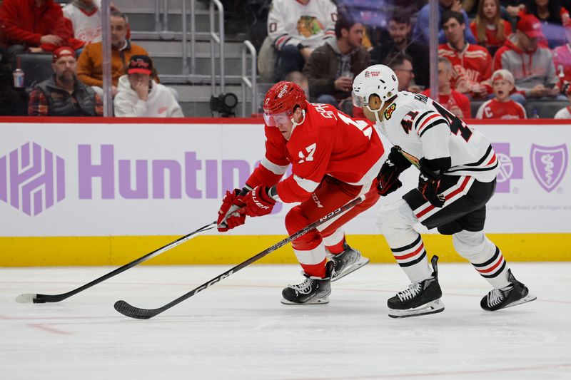 Nov 30, 2023; Detroit, Michigan, USA; Detroit Pistons guard Stanley Umude (17) skates with the puck defended by Chicago Blackhawks defenseman Isaak Phillips (41) in the second period at Little Caesars Arena. Mandatory Credit: Rick Osentoski-USA TODAY Sports