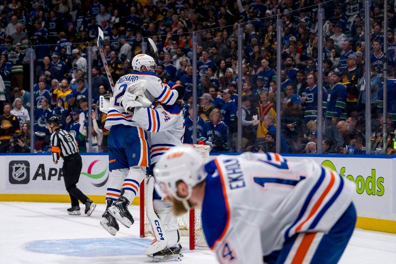 May 20, 2024; Vancouver, British Columbia, CAN;  As Edmonton Oilers defenseman Mattias Ekholm (14) picks up the game puck defenseman Evan Bouchard (2) and goalie Stuart Skinner (74) celebrate their victory over the Vancouver Canucks in game seven of the second round of the 2024 Stanley Cup Playoffs at Rogers Arena. Mandatory Credit: Bob Frid-USA TODAY Sports