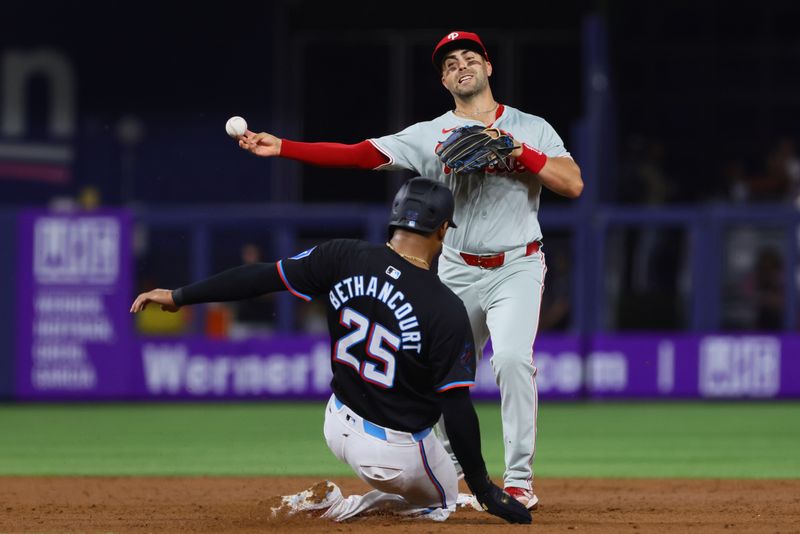 May 10, 2024; Miami, Florida, USA; Philadelphia Phillies second baseman Whit Merrifield (9) turns a double play as Miami Marlins catcher Christian Bethancourt (25) slides at second base during the third inning at loanDepot Park. Mandatory Credit: Sam Navarro-USA TODAY Sports