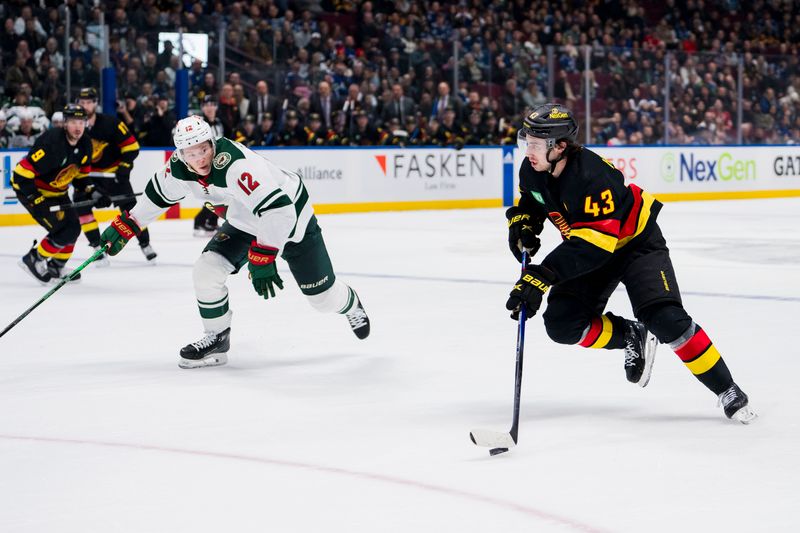 Dec 7, 2023; Vancouver, British Columbia, CAN; Minnesota Wild forward Matt Boldy (12) watches Vancouver Canucks defenseman Quinn Hughes (43) handle the puck in the first period at Rogers Arena. Mandatory Credit: Bob Frid-USA TODAY Sports